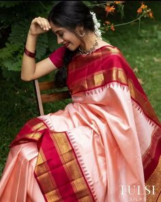 a woman in a red and gold sari sitting on a chair with her hands behind her head