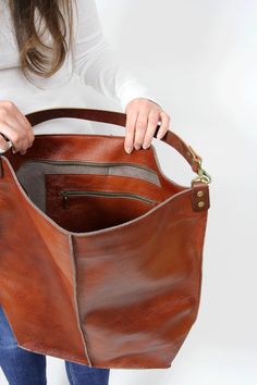 Cognac brown leather hobo This brown large tote bag is made from high quality italian leather. Spacious interior provides room for all the daily essentials and more. There is an inside zippered pocket. This bag is perfect as your everyday bag, which can fit an IPAD, laptop, A4 files, books, magazines, cosmetic bag as well as many accessories. This bag has top zipper closure for safety. Height: 18,5 inch (47 cm) Width: 18,1 inch (46 cm) Length of handle: 19,3 inch (49 cm) Bottom width: 13,4x 5,5 Large Capacity Cognac Hobo Shoulder Bag, Cognac Large Capacity Hobo Shoulder Bag, Brown Satchel With Zipper Pocket For Errands, Cognac Leather Bucket Bag With Large Capacity, Everyday Cognac Hobo Bag With Leather Lining, Brown Hobo Bucket Bag With Removable Pouch, Brown Leather-lined Hobo Bag For Everyday, Shopping Hobo Bag In Cognac With Removable Pouch, Brown Large Capacity Hobo Bag For On-the-go