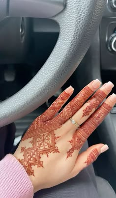 a woman's hand with henna on it in the driver's seat