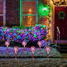 some candy canes in front of a house decorated with christmas lights and garlandes