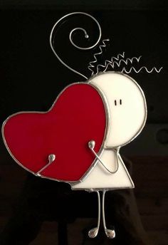 a red and white heart shaped brooch with a person holding it in the air