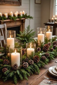 a table topped with candles and evergreen greenery next to a fire place filled with pine cones