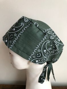 a white mannequin head wearing a green bandana with black and white designs on it