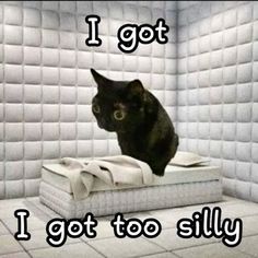 a black cat sitting on top of a mattress in a room with white tile walls