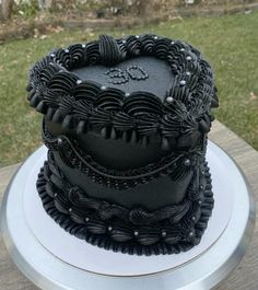 a black cake sitting on top of a white plate in front of a grass covered field