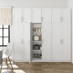 a kitchen with white cupboards and wooden floors