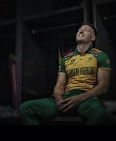 a man sitting on top of a bench wearing a green and yellow shirt