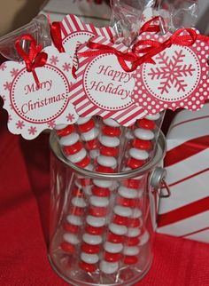 some candy sticks are in a clear cup with red and white snowflakes on them