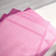 three pink notebooks sitting next to each other on top of a white tablecloth