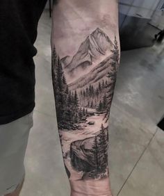 a man's arm with a mountain scene and trees on the inside of it