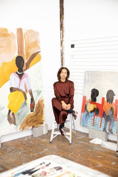 a woman sitting on a chair in front of paintings