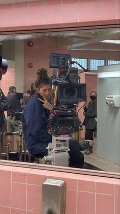 a woman standing in front of a mirror next to a camera