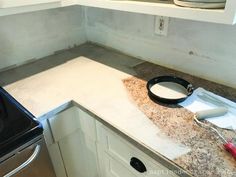 a stove top oven sitting inside of a kitchen next to a counter with a pan on it