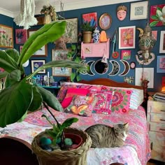 a cat laying on top of a bed next to a potted plant