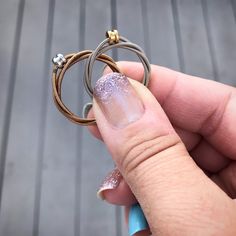 a person holding a ring in their left hand with two rings on top of it