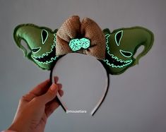 a hand holding up a mickey mouse ears headband with glow in the dark on it