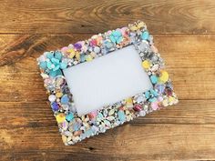 an empty photo frame made out of rocks and pebbles on a wooden table with a white blank space in the middle