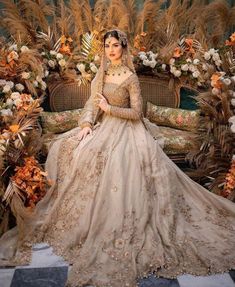 a woman in a wedding dress sitting on a couch with flowers and plants around her