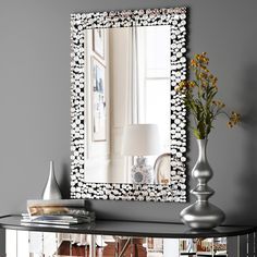 a large mirror sitting on top of a table next to a vase