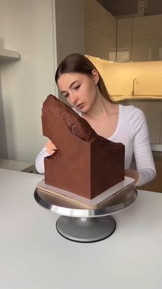 a woman sitting at a table with a chocolate cake in front of her