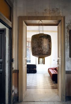 an open door leading to a living room with a couch and lamp hanging from the ceiling