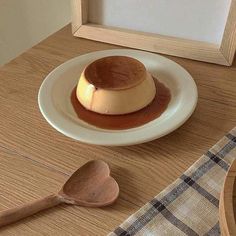 a small dessert on a white plate next to a wooden spoon and framed photograph in the background