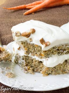 carrot cake with white frosting and nuts on a plate next to some carrots