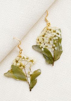 A pair of dried floral earrings in white. Botanical Gold Earrings With Pressed Flowers, Gold Botanical Earrings With Pressed Flowers, Nature-inspired Gold Flower Earrings With Pressed Flowers, Nature-inspired Gold Earrings With Pressed Flowers, Nature-inspired Dangle Earrings With Pressed Flowers, Nature-inspired Green Earrings With Pressed Flowers, White Birth Flower Earrings, Nature-inspired, White Nature-inspired Earrings With Birth Flower, White Birth Flower Earrings In Nature-inspired Style