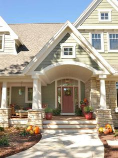 the front entrance to a house with pumpkins on the steps