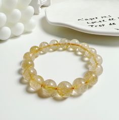 🌟 Discover the allure of our Golden Rutilated Quartz Bracelet, a symbol of elegance and natural wonder. This bracelet features delicately pale yellow beads, imbued with naturally occurring golden strands, presenting a simple yet sophisticated aesthetic. 💛 Each bead of this exquisite bracelet is a testament to nature's artistry, displaying a unique pattern of golden rutilations within the quartz. Available in three bead sizes - 8mm, 10mm, and 12mm - you can choose the perfect fit for your style and comfort. 🍀 Rutilated quartz is not only known for its stunning appearance but also for its believed benefits. Often regarded as a stone of good luck, it's thought to bring about clarity, spiritual growth, and emotional healing. The golden threads within the quartz are said to symbolize wealth Elegant Yellow Crystal Bracelet With Round Beads, Elegant Yellow Gemstone Beads Bracelets, Elegant Yellow Bracelets With Gemstone Beads, Elegant Yellow Bracelets With 8mm Beads, Bead Sizes, Golden Rutilated Quartz, Sophisticated Aesthetic, Golden Hair, Energy Bracelets