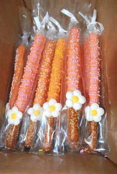 several carrots wrapped in plastic and decorated with daisies on the top, along with corn cobs