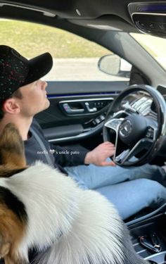 a man sitting in the driver's seat of a car with his dog