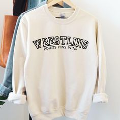 Show off your wrestling pride with our high-quality wrestling sweatshirts, perfect for athletes, fans, and parents alike. These sweatshirts are designed to keep you comfortable and warm, whether you're on the sidelines cheering at a tournament, supporting your team, or gearing up for practice.  Crafted for durability and style, our wrestling apparel is a must-have for anyone passionate about the sport. The bold designs and motivational themes make these sweatshirts ideal for showing your dedicat School Wrestling Shirts Ideas, Wrestling Designs For Shirts, Wrestling Sweatshirts, Wrestling Shirts Ideas, Clothing Practice, Wrestling Apparel, High School Sport, Wrestling Mom Shirts, Sideline Cheer