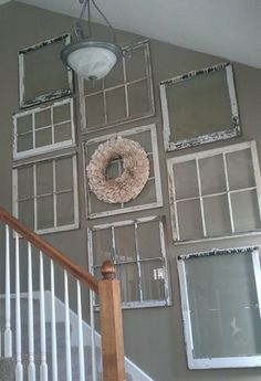 an old window frame is hung on the wall next to a stair case and framed pictures