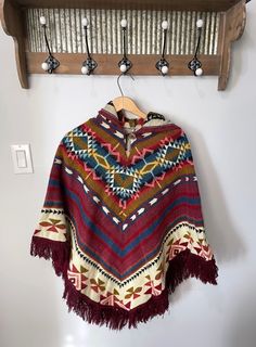 🌟 Now Shipping With Courier Because Of Canada Post Strike 🌟 Infuse a touch of boho flair into your closet with our enchanting artisanal ponchos. Meticulously fashioned by our skilled craftsmen in Ecuador, these ponchos exhibit a pullover style accompanied by a hood, and they boast an unparalleled tribal pattern for a truly distinctive look. Dimensions:  Length: 32 in (with fringe 36 in) Width: 41 in ♥ Experience the comfort of our exquisite tribal ponchos, crafted for both warmth and durabilit Bohemian Alpaca Outerwear For Fall, Bohemian Alpaca Shawl For Fall, Bohemian Alpaca Cape For Fall, Bohemian Multicolor Poncho For Fall, Bohemian Multicolor Alpaca Outerwear, Multicolor Bohemian Poncho For Fall, Artisan Alpaca Poncho For Fall, Bohemian Hooded Brown Poncho, Bohemian Alpaca Shawl