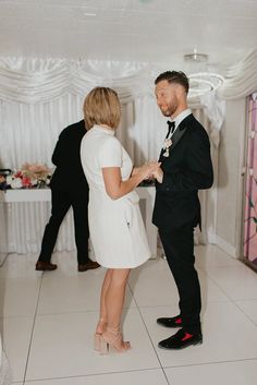 a man in a tuxedo standing next to a woman in a white dress