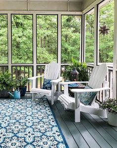 two white chairs sitting on top of a blue and white rug in front of windows