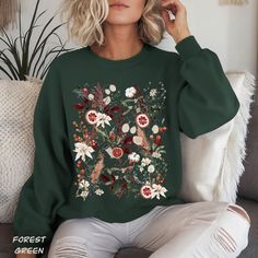 Introducing our Fall& Winter Cottage Core Sweatshirt, a charming blend of style and nature. This cozy sweater is adorned with a mix of painted fall and winter flowers, berries, and both dried and pressed flowers ( painted & real), bringing the warmth of nature to your wardrobe during the colder months. Made with air-jut spun yarn for a soft feel, this pre-shrunk, classic fit sweater is both stylish and comfortable. Perfect for nature enthusiasts, Cottagecore lovers, and anyone who appreciates the charm of pressed flowers. So pick one for yourself of your loved onces and embrace the beauty of nature during the colder months. PRODUCT SPEC. * 50% cotton, 50% polyester * Pre-shrunk * Classic fit * 1x1 athletic rib knit collar with spandex * Air-jet spun yarn with a soft feel * Double-needle st Green Tops With Plant Print For Fall, Winter Floral Print Cotton Tops, Green Holiday Tops For Spring, Green Tops For Fall Holiday, Green Tops For Spring Holiday, Printed Green Tops For Winter, Botanical Relaxed Fit Tops For Fall, Witch Sweater, Winter Cottagecore