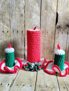 two crocheted candles are sitting next to each other on a wooden surface with pine cones