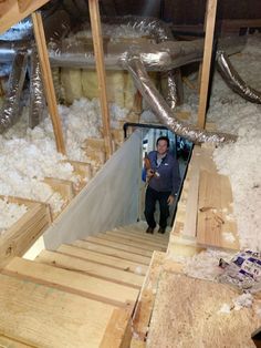 a man standing in the doorway of an unfinished room with wood flooring and insulation