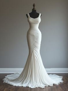 a white wedding dress on a mannequin in front of a gray wall and wooden floor