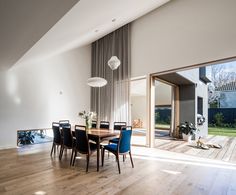 a dining room table with blue chairs in front of a sliding glass door that leads to the backyard