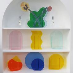 a white shelf filled with different colored vases on top of it's shelves