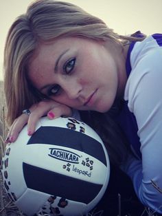 a beautiful young woman laying on top of a field next to a white and black soccer ball