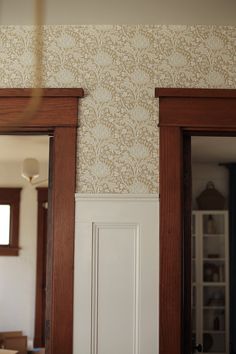 an open door is shown in front of a wallpapered room with wood trim