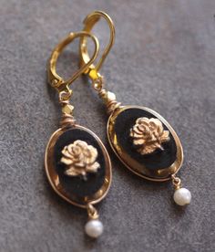 "Created with 1930s recovered glass cabochons. Black glass and gold gilded glass rose. Set in jewelers bronze. Embellished with fine cultured pearls. Adjustable matinee length 24\" chain. Original concept, design and presentation. Feather light earrings." Elegant Gold Jewelry From Vintage Collection, Formal Gold Earrings With Rose Design, Gold Brass Cabochon Earrings, Gold Cabochon Brass Earrings, Gold Brass Earrings With Cabochon Detail, Elegant Gold Vintage Jewelry, Victorian Gold Cabochon Earrings, Gold Victorian Cabochon Earrings, Elegant Vintage Cabochon Jewelry