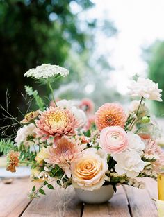 a vase filled with lots of flowers on top of a wooden table