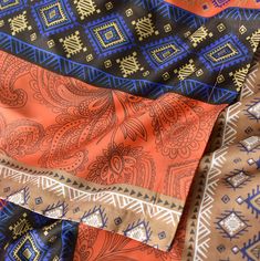 an assortment of different colored and patterned fabrics, including one with blue, orange, and brown designs