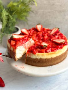 a strawberry cheesecake on a plate with a slice cut out and ready to be eaten