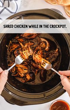 someone is holding a fork in a slow cooker filled with shredded chicken while the crockpot has been cooked